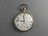 a silver pocket watch that is on a gray surface