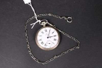 une montre de poche en argent attachée à une chaîne, posée sur une surface noire