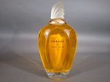 an image of a bottle of perfume with a white feather on top