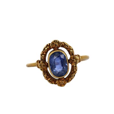 gros plan d'une bague en or avec une pierre bleue
