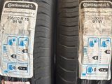 des pneus posés sur une étagère dans un magasin, sur lesquels sont collés des autocollants
