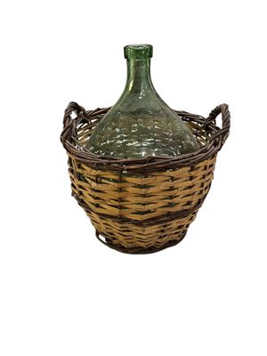 a green glass bottle sitting inside of a wicker basket