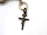 a small cross hanging from a keychain on a white surface