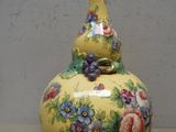 un vase jaune orné de fleurs peintes, posé sur une table