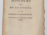 un vieux livre posé sur une table à côté d'une tasse de café