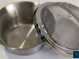 a metal strainer with a metal lid on a white surface
