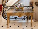 a marble table with a vase of flowers on it in front of a spiral staircase