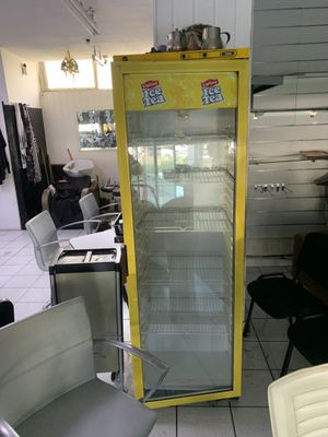 un réfrigérateur jaune au milieu d'une pièce où se trouvent des chaises et des tables
