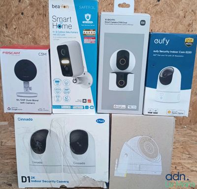 four boxes of smart home cameras sitting on top of a wooden table