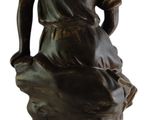 statue of a man sitting on a rock with a hat on his head