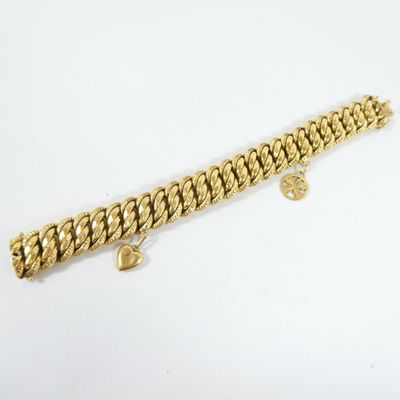 gros plan d'un bracelet en or sur une surface blanche