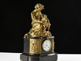 a gold statue of a woman sitting on top of a clock