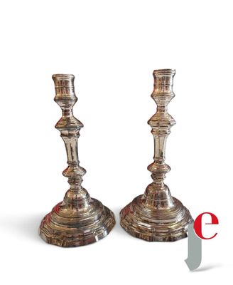une paire de bougeoirs en argent sur fond blanc, avec la lettre « e »