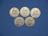 six pièces d'argent de tailles et de formes différentes sur un fond bleu