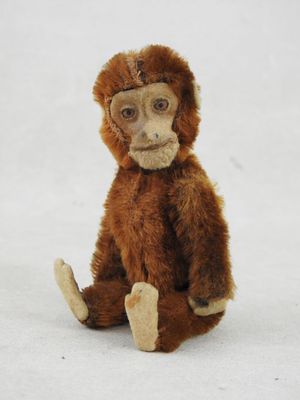 un petit singe en peluche assis par terre