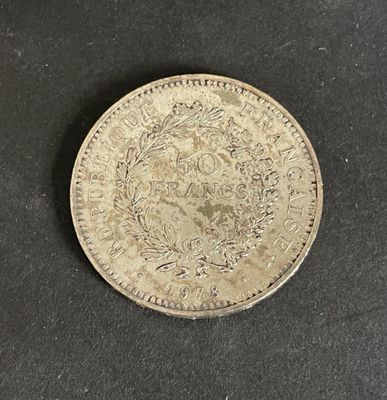 a silver coin on a black surface with a white background