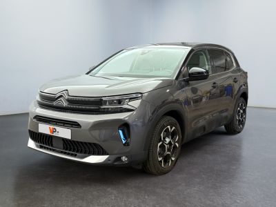 Une Citroën grise est garée dans une pièce au sol noir.