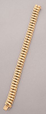 a gold bracelet with a clasp on a gray surface