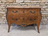 une commode ancienne avec un plateau en marbre, placée devant un mur en pierre