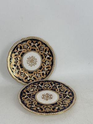 deux assiettes ornées de motifs dorés et bleus, posées sur une surface blanche
