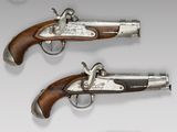 two silver - plated pistols with wooden grips and a silver - plated case