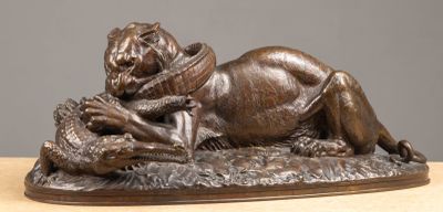 bronze statue of a lion laying on a rock with a bird in it ' s mouth