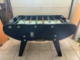 une table de baby-foot dans un garage, avec la porte du garage en arrière-plan