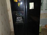a black refrigerator in the corner of a room with a mirror