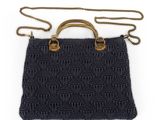 a black knitted bag with brass handles and a chain