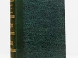 an old book with a green cover sitting on a white surface