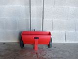concrete floor with a red cart in it and a white wall in the background