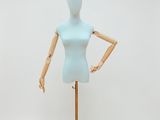 un mannequin féminin posé sur un socle doré, devant un fond blanc