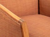 the arm of a chair with a wooden frame and a brown upholstered seat