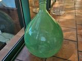 un grand vase vert posé sur un sol carrelé près d'une fenêtre