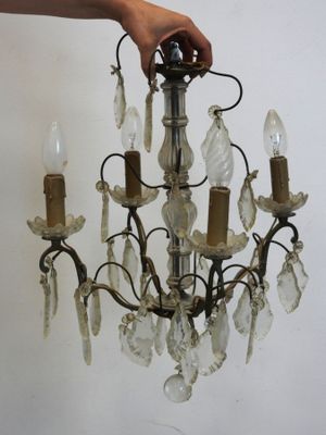 une personne tenant un lustre auquel sont suspendues plusieurs ampoules