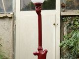 un lampadaire rouge surmonté d'un chat, devant une porte