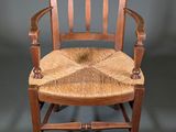 an old wooden chair with a woven seat on a grey background