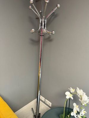 a vase with flowers on a table next to a coat rack
