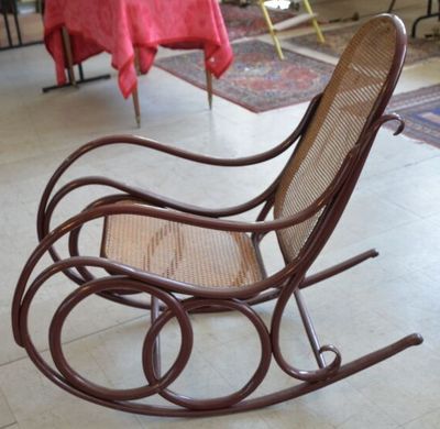 un fauteuil à bascule dans une pièce, avec une table en arrière-plan