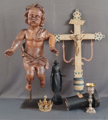 a statue of a child holding a cross next to a candle