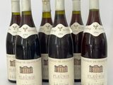 six bouteilles de vin sont alignées sur une surface blanche