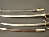 three old swords are displayed on a table with a black background