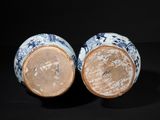 pair of blue and white vases on a black surface with a black background