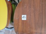 une chaise en bois sur laquelle est collé un autocollant, à côté d'une pile de chaises colorées