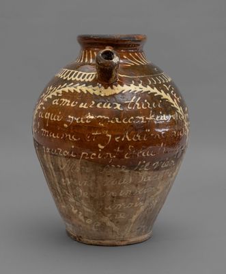 un vieux vase marron portant une inscription sur un fond gris