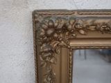 a picture of a gold framed mirror hanging on a wall