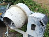 a cement mixer sitting next to a trailer on the side of the road