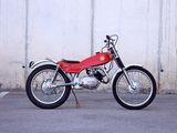 a red motorcycle parked in a parking lot next to a white wall