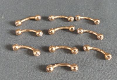 six paires de piercings chirurgicaux plaqués or sur un fond gris