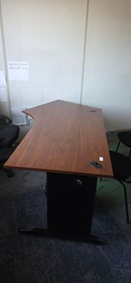 a wooden table with a black chair in the corner of the room